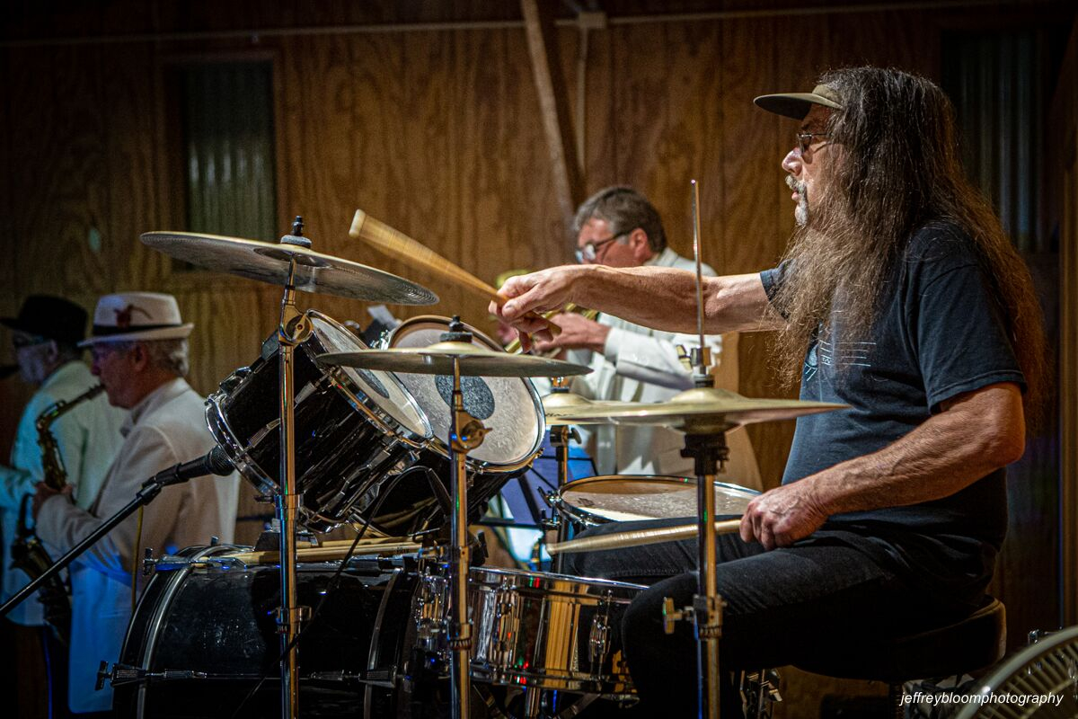 a musician playing the drums with another musician in the background